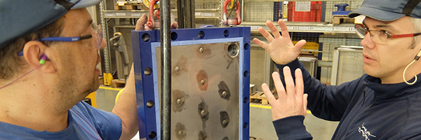 Two men discussing in welded heat exchanger workshop